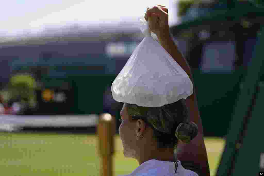 Ukraine's Marta Kostyuk places a bag of ice on her head as she tries to keep cool during a break as she plays Spain's Paula Badosa in a women's singles match on day five of the Wimbledon tennis championships in London.