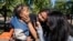 FILE - Anmani Rendon of Venezuela holds her 2-year-old daughter, Sofia Barragan, as med student Christina Guyn shines a light inside her mouth outside of the 12th District police station where migrants are camped, Oct. 7, 2023, in Chicago. 