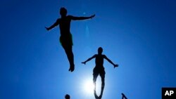 Young people jump into the water to cool down on a sweltering hot day at the Mediterranean Sea in Beirut, Lebanon.