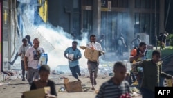 People run with merchandise as crowds leave shops with looted goods amid a state of unrest in Port Moresby on Jan. 10, 2024. 
