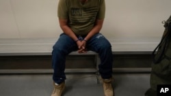 FILE - An immigrant considered a threat to public safety and national security waits to be processed by U.S. Immigration and Customs Enforcement agents at the ICE Metropolitan Detention Center in Los Angeles, after an early morning raid, June 6, 2022.