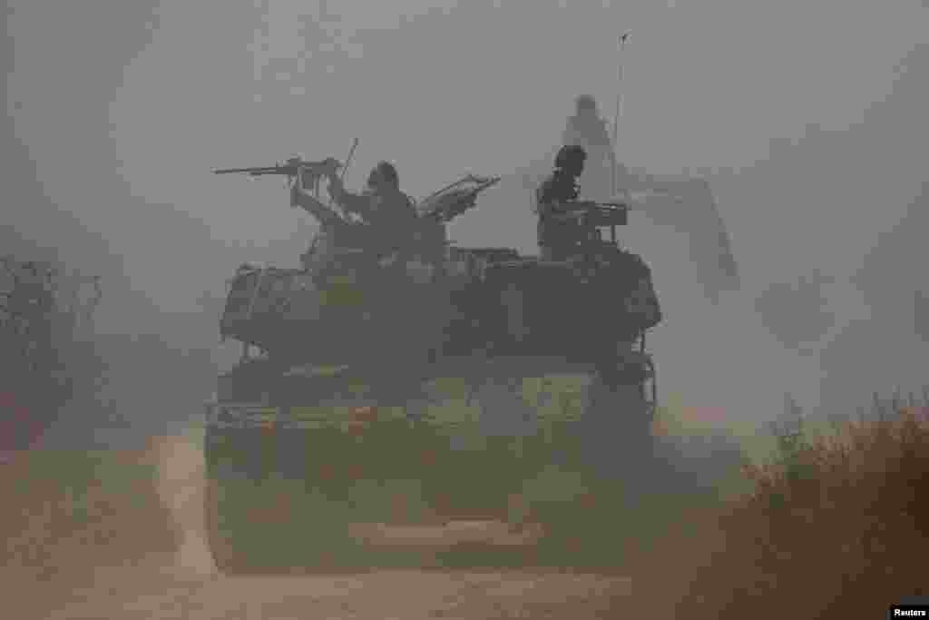 Israeli soldiers ride atop an artillery unit near the Israeli side of the border between Israel and the Gaza Strip.