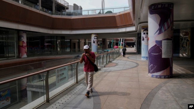 FILE - A man plays a harmonica while walking by a deserted Evergrande city plaza in Beijing, Sept. 18, 2023. China's languishing economy could encourage Beijing to become more cooperative with the U.S. on North Korea, one expert thinks.