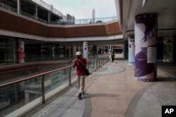 Seorang pria berjalan di plaza Evergrande yang ditinggalkan penyewa di Beijing, 18 September 2023. (Foto: Andy Wong/AP Photo)