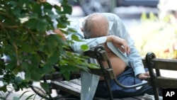 FILE - A man rests on a shady bench on a hot summer day in New York, July 15, 2024.