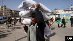 FILE — A man carries bags of humanitarian aid in Rafah in the southern Gaza Strip, Nov. 26, 2023. The United States on Tuesday sent the first of three military planes to Egypt with humanitarian aid for Gaza.