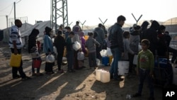 Members of the Abu Jarad family, who were displaced by the Israeli bombardment of the Gaza Strip, queue for water at a makeshift tent camp in the Muwasi area, southern Gaza, Jan. 1, 2024.