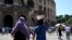 FILE - Tourists protect themselves from the sun as they walk near the Colosseum on July 11, 2024 in Rome. July temperatures reached the highest average on record worldwide, according to a U.S. environmental agency report. 