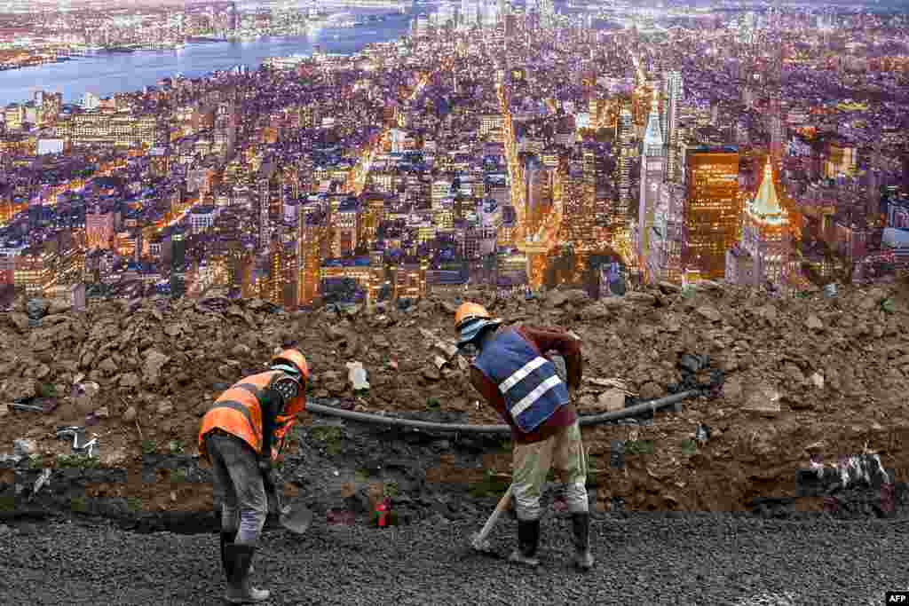 Construction workers prepare to build foundations along a street next to a billboard with an image of New York City in Phnom Penh, Cambodia.