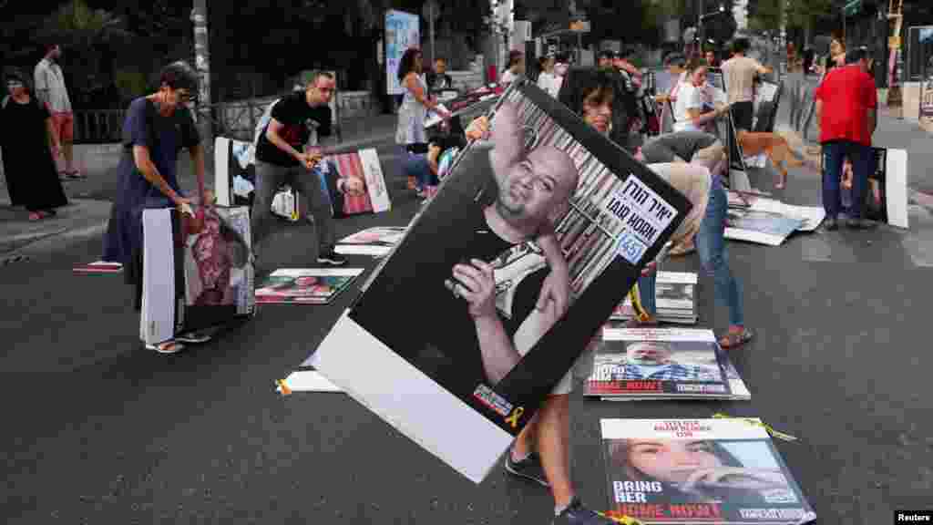 Family members and supporters of hostages who were kidnapped during the deadly October 7 attack, remove 107 pictures of hostages after placing them outside Israeli Prime Minister Benjamin Netanyahu's residence in Jerusalem.