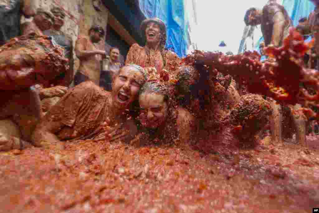 Revelers lie in a pool of squashed tomatoes during the annual &quot;Tomatina&quot; tomato fight fiesta, in the village of Bunol near Valencia, Spain.