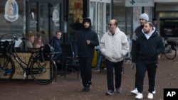Migrants walk outside a shopping mall in Ter Apel, northeastern Netherlands, Nov. 9, 2023, as the country heads into elections with migration a key topic.