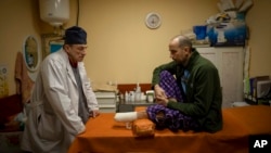 El médico ucraniano Yurii Kuznetsov habla con la víctima de las minas terrestres Oleksandr Kolisnyk en el hospital de Izium, Ucrania, el domingo 19 de febrero de 2023. (Foto AP/Vadim Ghirda, Archivo)