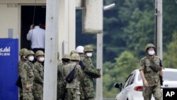 Japanese Self Defense Force members gather near a facility in a base firing range, following a deadly shooting in Gifu, central Japan, June 14, 2023. (Kyodo News via AP)