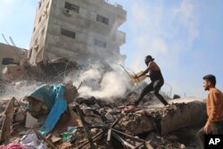Palestinians extinguish the fire on the rubble of destroyed buildings in the Israeli bombardment of the Gaza Strip in Nusseirat refugee camp, central Gaza Strip, Nov. 17, 2023.