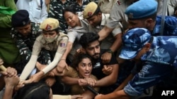FILE - Wrestler Vinesh Phogat, center below, an Asian Games champion, is among those detained by police while attempting to march to India's new parliament, in New Delhi, May 28, 2023.