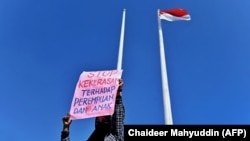 Seorang pedemo menunjukkan poster bertulikan stop kekerasan terhadap perempuan di DPR Aceh, Banda Aceh, 23 Desember, 2023. (Foto: Chaideer Mahyuddin/AFP)