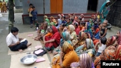 FILE — Bangladeshi women wait for a volunteer to distribute their loan money collected from a microfinance agency at Manikganj,100 km (62 miles) from the capital Dhaka, Sept. 24, 2005.