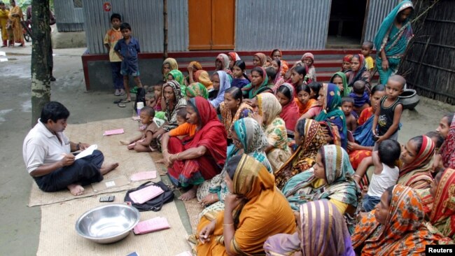 FILE - Bangladeshi women wait for a volunteer to distribute their loan money collected from a microfinance agency at Manikganj, 100 kilometers (62 miles) from the capital Dhaka, Sept. 24, 2005.