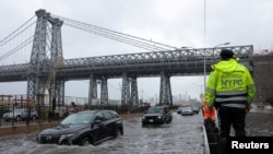 A police officer from the NYPD Highway Patrol looks to motorists drive through a flooded street after heavy rains brought flooding across the mid-Atlantic and Northeast, at the FDR Drive near the Williamsburg Bridge in New York, Sept. 29, 2023.