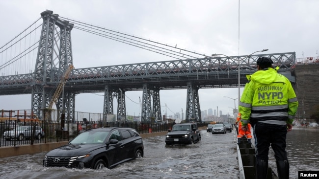 A police officer from the NYPD Highway Patrol looks to motorists drive through a flooded street after heavy rains brought flooding across the mid-Atlantic and Northeast, at the FDR Drive near the Williamsburg Bridge in New York, Sept. 29, 2023.