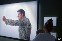 Seorang pengunjung melihat pajangan yang menampilkan veteran perang Ben Roberts-Smith di Australian War Memorial di Canberra, Australia, Jumat, 2 Juni 2023. (AP/Rod McGuirk)