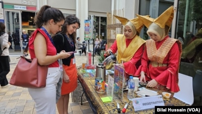 Indonesian women serve tea to visitors in front of their country's pavilion in Dubai, United Arab Emirates, on Dec. 6, 2023.