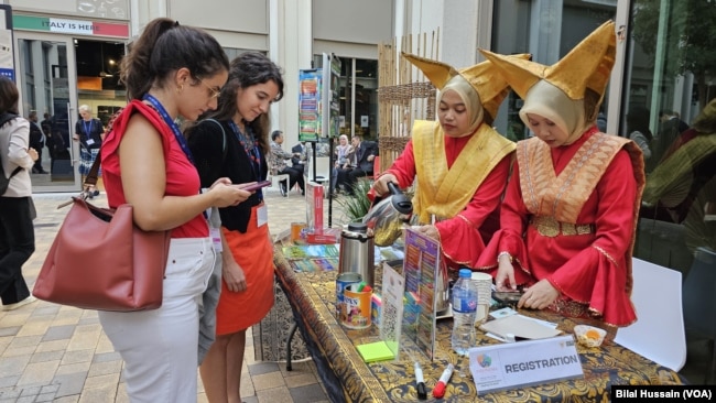 Indonesian women serve tea to visitors in front of their country's pavilion in Dubai, United Arab Emirates, on Dec. 6, 2023.