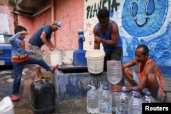 People extract water from an unknown source in the low-income neighborhood of Petare, in Caracas, Venezuela, May 12, 2023.