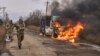 In this photo provided by Ukraine's military, Ukrainian soldiers pass by a bus burning after a Russian drone hit it near Bakhmut, Donetsk region, Ukraine, Nov. 23, 2023.