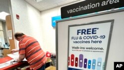FILE - A sign for flu and COVID vaccinations is displayed at a pharmacy in Palatine, Ill., Sept. 13, 2023. 