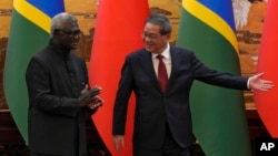 Chinese Premier Li Qiang, right, shows the way to his Solomon Islands counterpart Manasseh Sogavare after they witnessed signing an agreement for both countries at the Great Hall of the People in Beijing, July 10, 2023. 