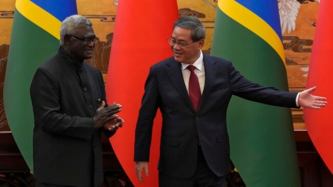 Chinese Premier Li Qiang, right, shows the way to his Solomon Islands counterpart Manasseh Sogavare after they witnessed signing an agreement for both countries at the Great Hall of the People in Beijing, July 10, 2023.