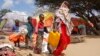 (FILE) A woman walks with her children, who fled amid drought, at a camp for the displaced people on the outskirts of Somalia.