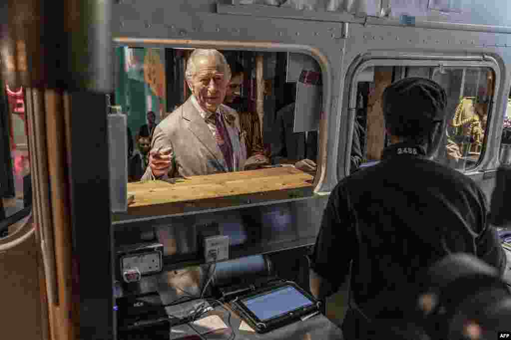 Britain's King Charles III orders food from a food truck during a visit to Nairobi Street Kitchen in Nairobi, Kenya.