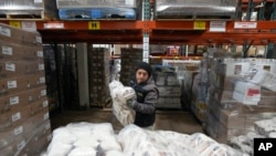 Driver Carlos Quezada loads rice on a pallet for distribution at Feeding Westchester in Elmsford, N.Y., Wednesday, Nov. 15, 2023. (AP Photo/Seth Wenig)