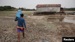 一名男子在巴西马瑙斯的干旱地区扛着一桶水前行。（2023年10月16日）