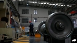 FILE - A worker checks on a cargo train wheel at the GEMAC Engineering Machinery during a media-organized tour in Xiangyang in China's Hubei Province, May 10, 2023. Chinese leader Xi Jinping promised to build more railway and trade links with Central Asia at a meeting May 19. 