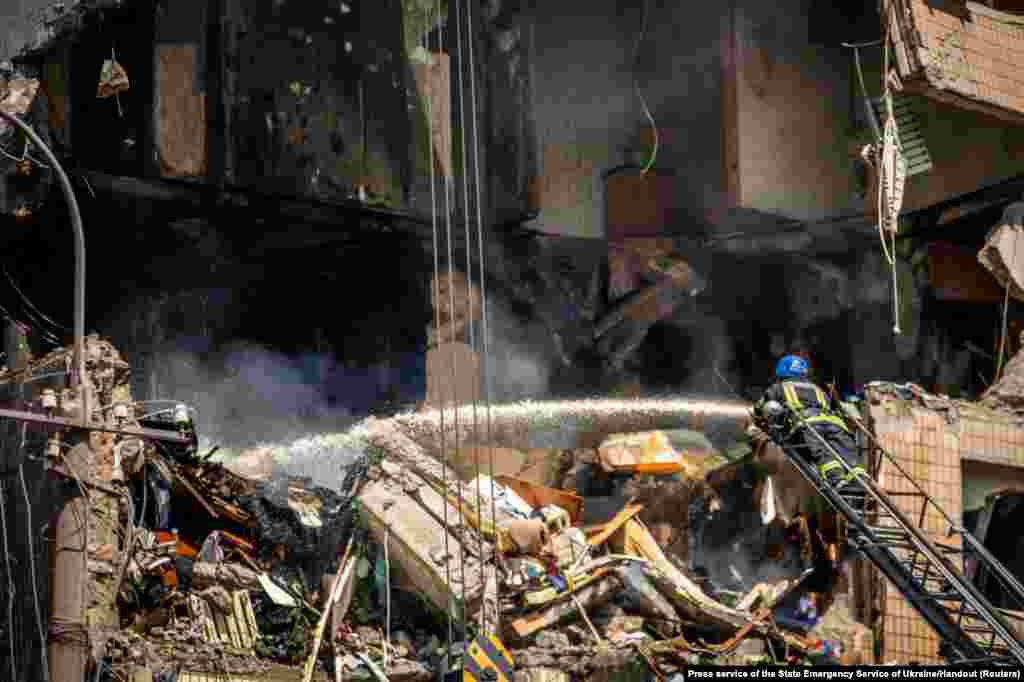 Пожарникар работи на место на станбена зграда тешко оштетена од руски ракетен напад во Криви Рих, Украина.