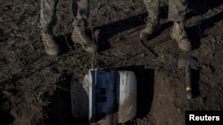 Ukrainian sappers dig up a rocket from a multiple launch system in a field, amid Russia's invasion of Ukraine, in Ukraine's southern Kherson region, Nov. 9, 2023.