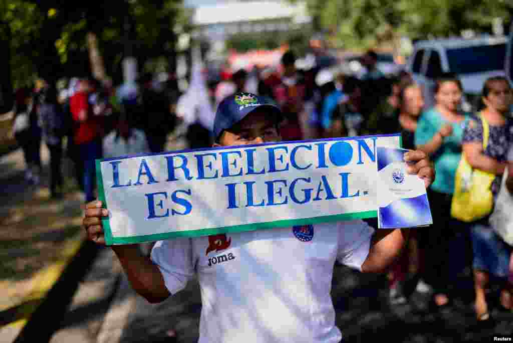 Un hombre sostiene un cartel que dice &quot;La reelección es ilegal&quot; durante la protesta para conmemorar el 32&ordm; aniversario de la firma de los acuerdos de paz en El Salvador.