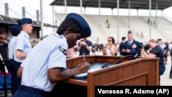 Airman 1st Class D'elbrah Assamoi, from Cote D'Ivoire, signs her U.S. certificate of citizenship after the Basic Military Training Coin Ceremony at Joint Base San Antonio-Lackland, in San Antonio, April 26, 2023. (Vanessa R. Adame/U.S. Air Force via AP)