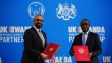 Secretário do Interior britânico, James Cleverly (esq), e o ministro das Relações Exteriores de Ruanda, Vincent Biruta, (dir) trocam documentos após assinarem um novo tratado, em Kigali, 5 de dezembro de 2023