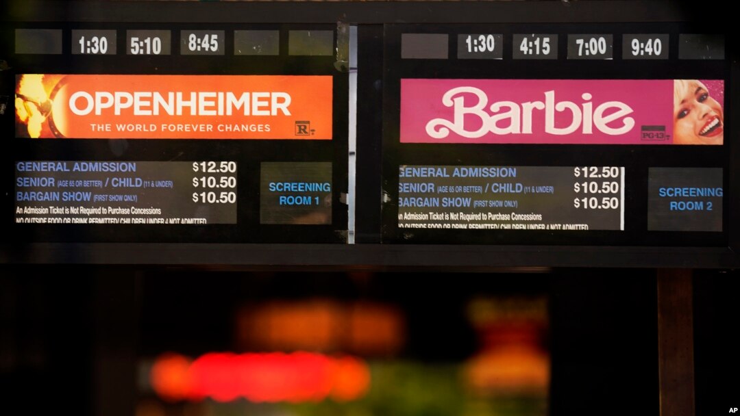 Showtimes for the films "Oppenheimer" and "Barbie" are pictured behind the box office window at the Los Feliz Theatre, July 28, 2023, in Los Angeles.