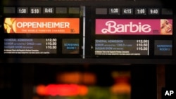 Showtimes for the films "Oppenheimer" and "Barbie" are pictured behind the box office window at the Los Feliz Theatre, July 28, 2023, in Los Angeles.