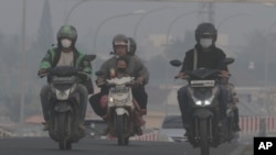 Riders wear masks as they pass through the haze from forest fires in Palembang, South Sumatra, Indonesia, Oct. 6, 2023.