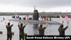 In this photo provided by South Korea Defense Ministry, South Korean navy sailors wave as the USS nuclear-powered submarine USS Annapolis arrives at a South Korean naval base on Jeju Island, South Korea, July 24, 2023.