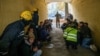 Rescued people, journalists and police officers take cover as an air-raid siren sounds during a Russian drone strike, in Kyiv, Ukraine, Oct. 17, 2022.