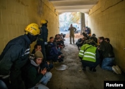 FILE - Rescued people, journalists and police officers take cover as an air-raid siren sounds during a Russian drone strike, in Kyiv, Ukraine, Oct. 17, 2022.
