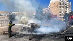 This undated handout photograph released Sept. 1, 2024, on the official Telegram account of Russia's Belgorod region governor, shows a firefighter extinguishing a burning car after a Ukrainian strike on the city of Belgorod. 